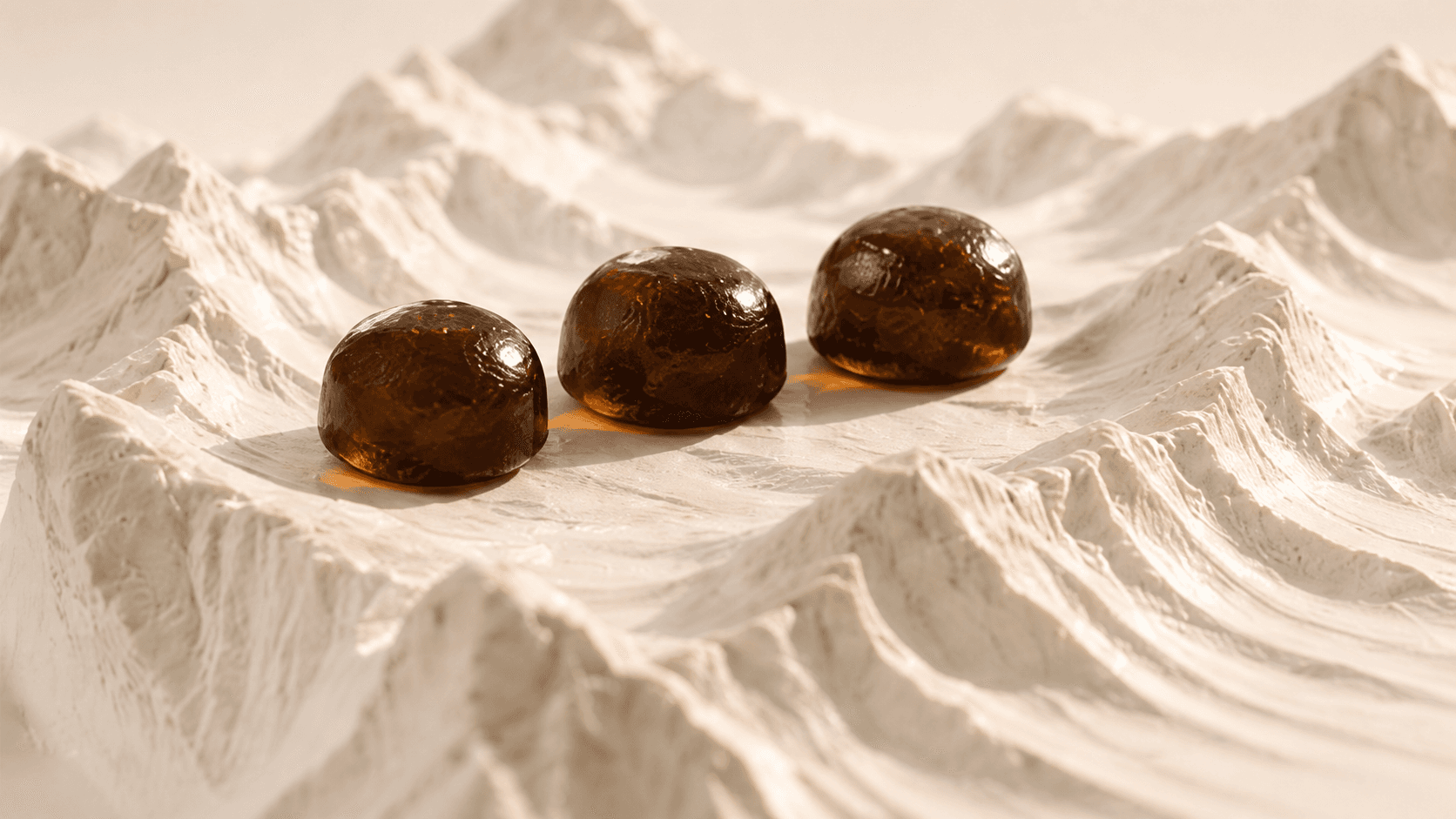 Three amber shilajit gummies on a sculpted Himalayan landscape